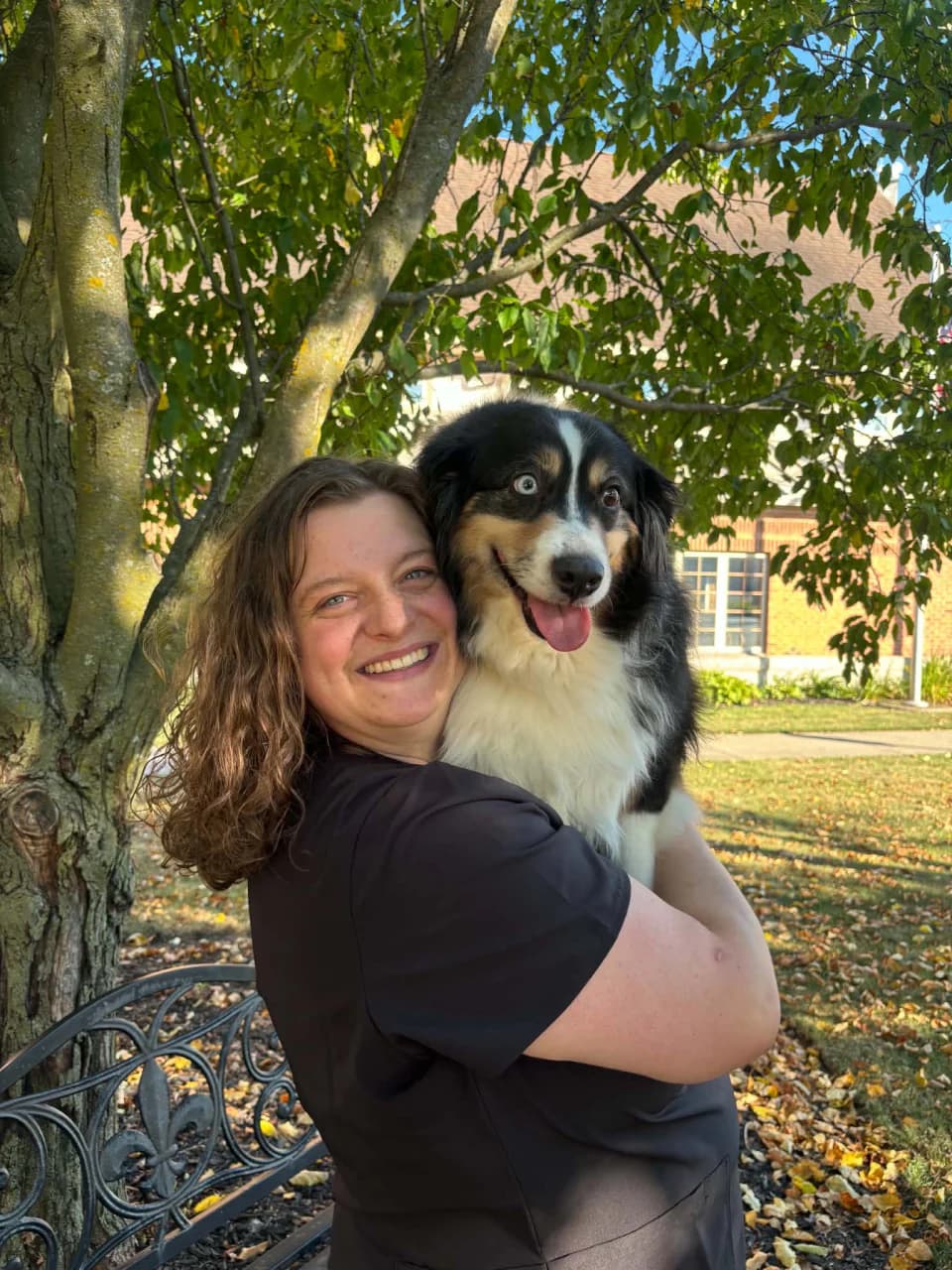 Gretchen smiling while holding her dog outdoors